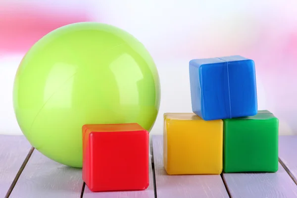 Яркий шар и красочные кубики на столе на ярком фоне — стоковое фото
