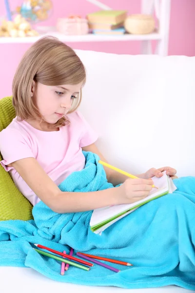 Little girl draws sitting on sofa in room — Stock Photo, Image