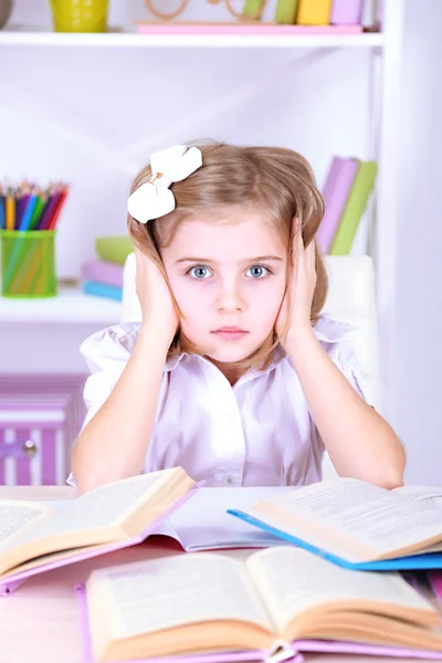 Little girl sitting at desk in room — Stock Photo, Image