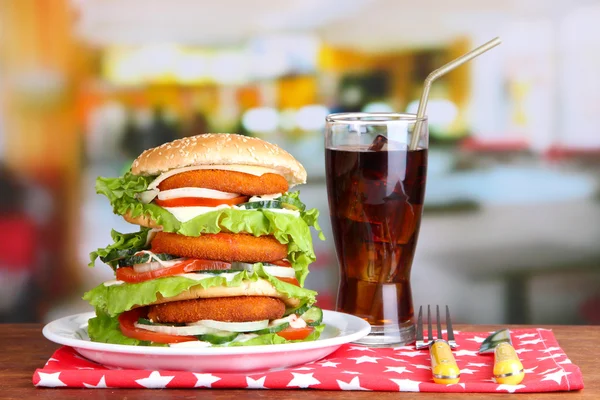 Velký burger na barevné desce a sklenici studené nápoje, na světlé pozadí — Stock fotografie