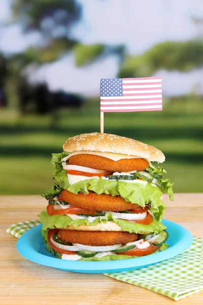 Hamburger enorme sul piatto di plastica di colore su sfondo luminoso — Foto Stock