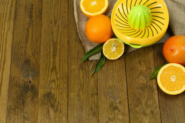 Цитрусовый пресс и фрукты на деревянном фоне — стоковое фото