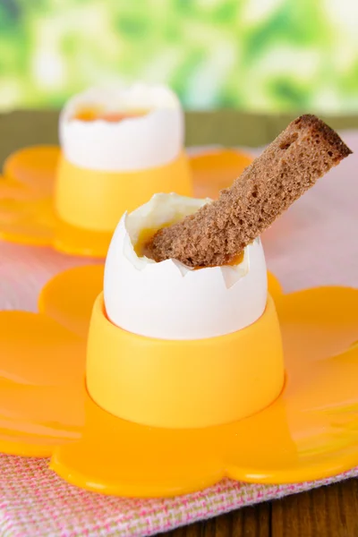 Вареные яйца в яичных чашках на столе на ярком фоне — стоковое фото