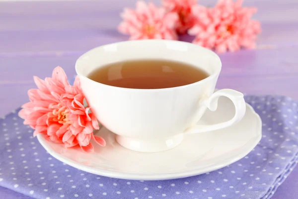 Pink chrysanthemums and cup of tea on wooden table — Stock Photo, Image