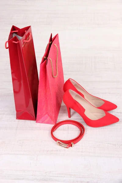 Sapatos femininos vermelhos bonitos, cinto e sacos de loja — Fotografia de Stock