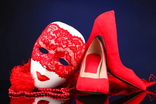 Belle scarpe rosse femminili e maschera di carnevale, su sfondo blu — Foto Stock