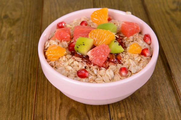 Deliciosa harina de avena con fruta en tazón en primer plano de la mesa — Foto de Stock