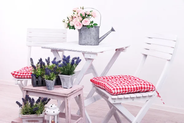 Cadeiras de jardim e mesa com flores em suporte de madeira sobre fundo branco — Fotografia de Stock