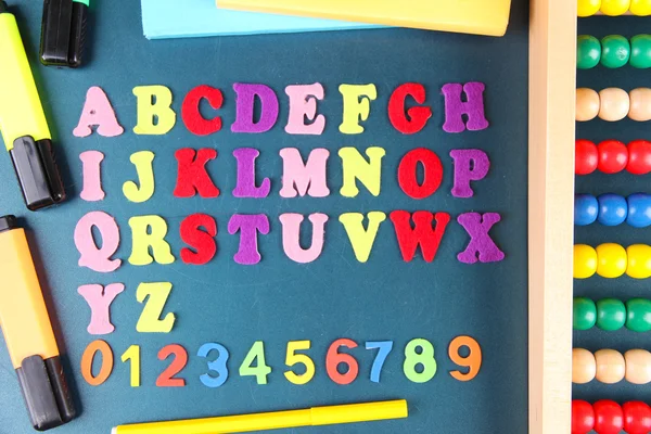 Números coloridos, ábaco, livros e marcadores no fundo da mesa da escola — Fotografia de Stock