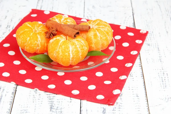 Reife süße Mandarinen mit Gewürzen auf Farbteller, auf Serviette, auf Holzgrund — Stockfoto