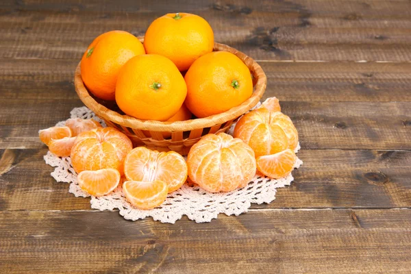 Rijpe zoete mandarijnen met kruiden in kom, op servet, op houten achtergrond — Stockfoto