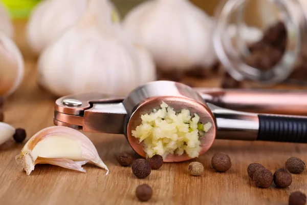 Πατήστε σύνθεση με σκόρδο, φρέσκο σκόρδο και γυάλινα βάζα με μπαχαρικά σε ξύλινα φόντο — Φωτογραφία Αρχείου