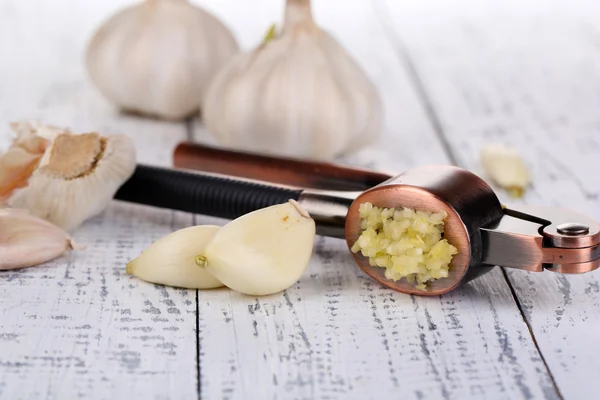 Garlic press on color wooden background — Stock Photo, Image