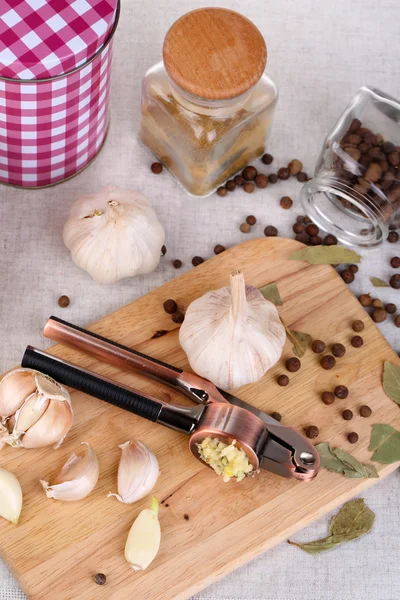 Összetétele a fokhagyma sajtó, friss fokhagyma és az üveg edény fűszerek fából készült háttér — Stock Fotó
