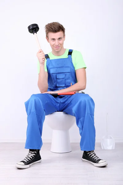 Klempner mit Toilettenkolben auf hellem Hintergrund — Stockfoto