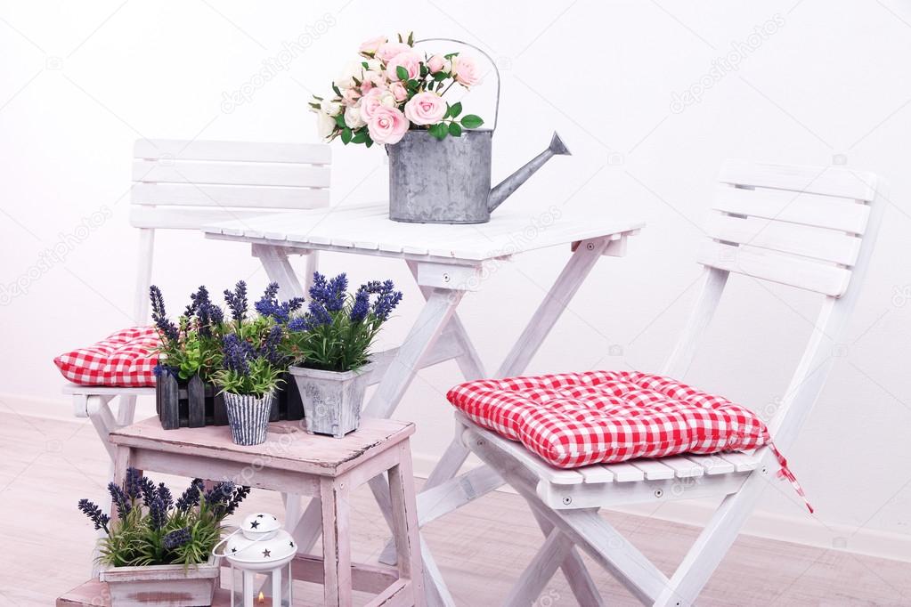 Garden chairs and table with flowers on wooden stand on white background