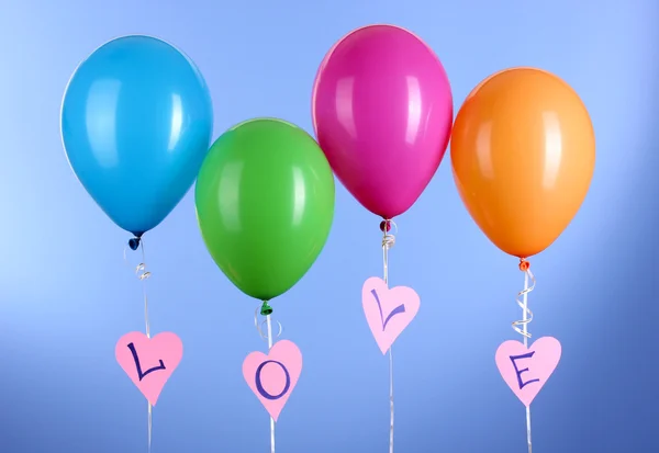 Kleurrijke ballonnen houdt woord "love" op blauwe achtergrond — Stockfoto