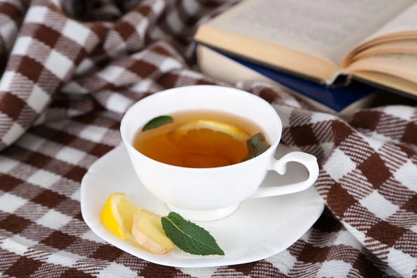 Φλιτζάνι τσάι με τζίντζερ σε καρό με ένα βιβλίο — Φωτογραφία Αρχείου