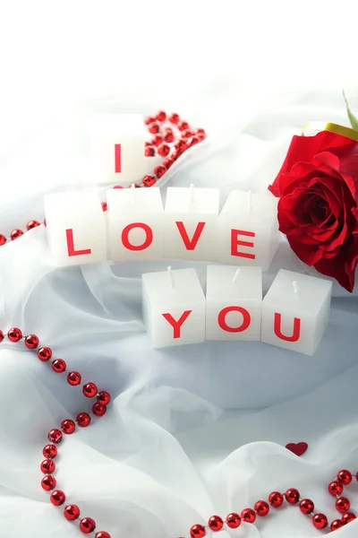Candles with printed sign I LOVE YOU, on white fabric background — стоковое фото