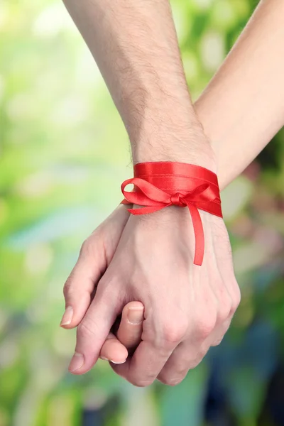 Mans and girls hands tied with ribbon on bright background — Stock Photo, Image