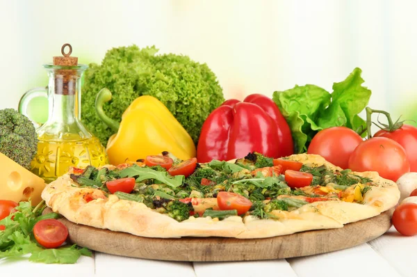 Tasty vegetarian pizza and vegetables on wooden table — Stock Photo, Image