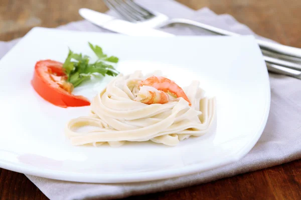 Pasta con gambas sobre plato blanco, sobre fondo de madera — Foto de Stock