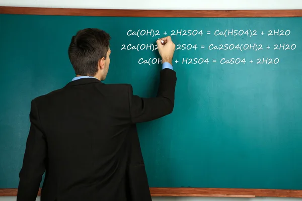 Young teacher near chalkboard in school classroom — Stock Photo, Image