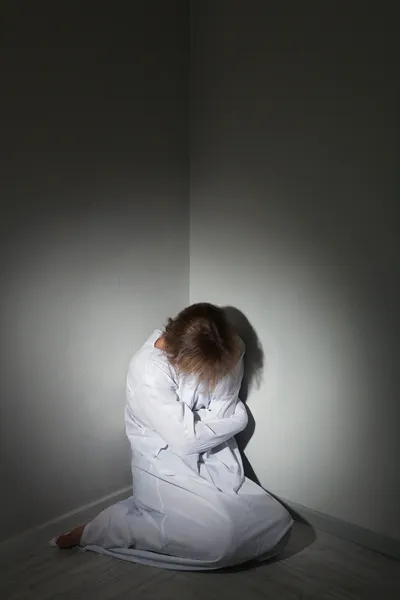 Mentally ill man in strait-jacket in room corner — Stock Photo, Image