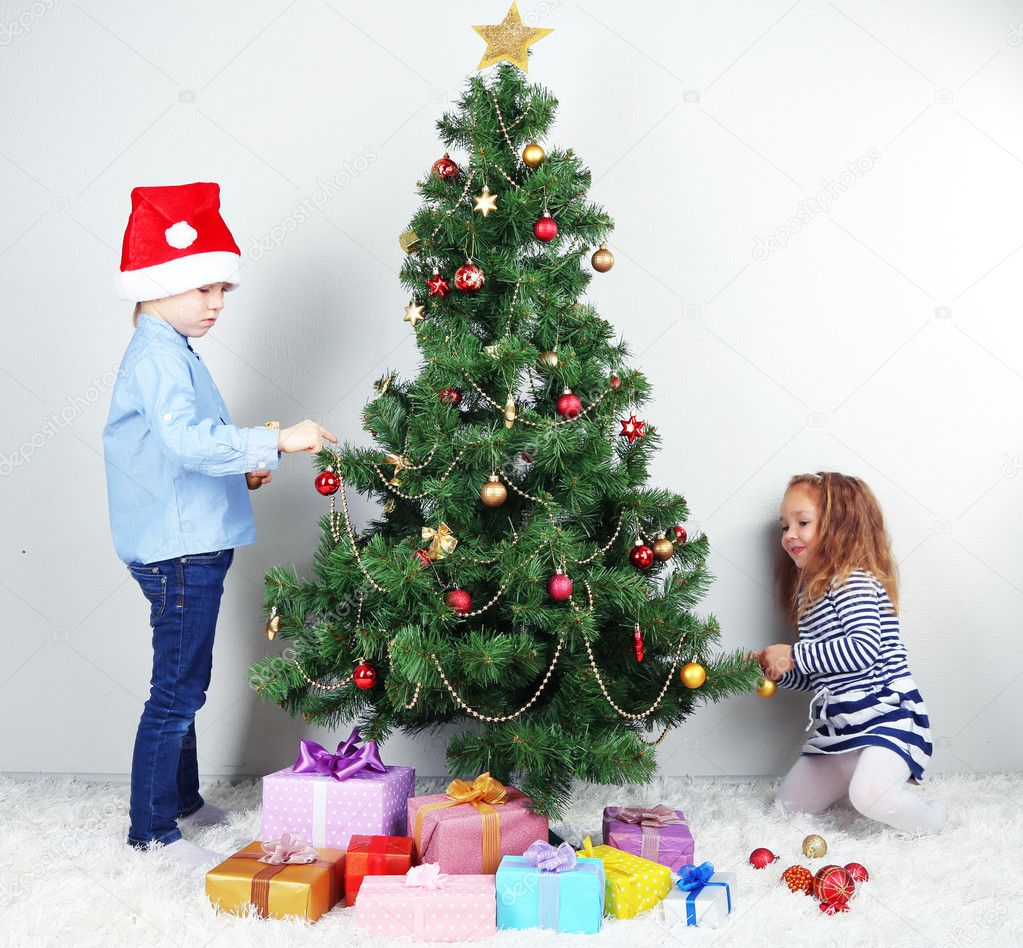 Kids decorating Christmas tree with baubles in room — Stock Photo © belchonock 39279573