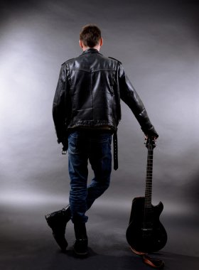 koyu renk arka plan üzerinde gitar ile genç müzisyen