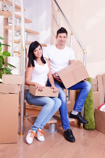 Young couple with boxes in new home on staircase background — Stock Photo, Image