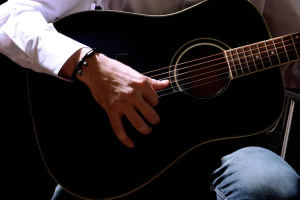 Jonge musicus spelen gitaar, close-up, op donkere achtergrond — Stockfoto