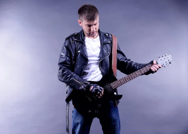 Joven músico tocando la guitarra sobre fondo gris —  Fotos de Stock