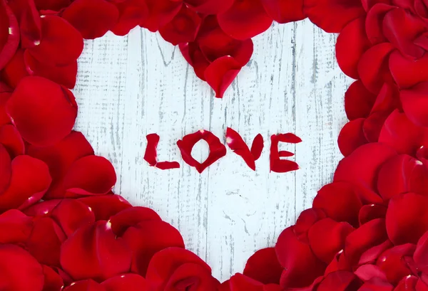 Beau coeur de pétales de rose rouge sur table en bois close-up — Photo