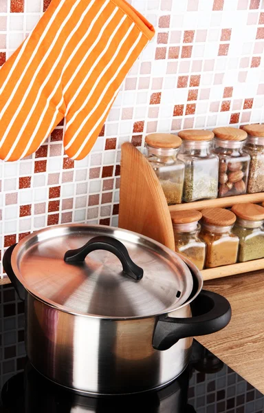Pot on stove in kitchen on table on mosaic tiles background — Stock Photo, Image