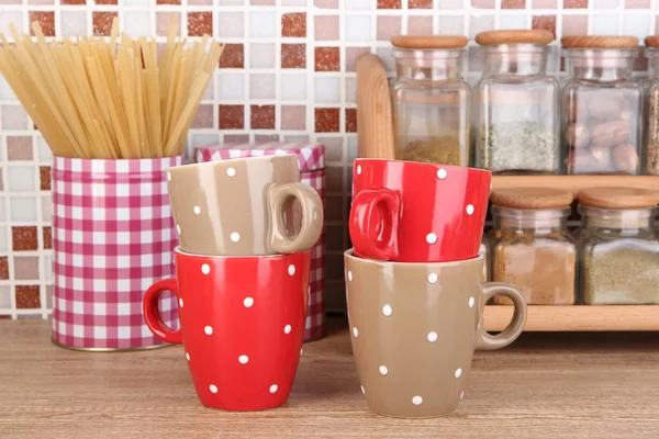 Cups in kitchen on table on mosaic tiles background — Stock Photo, Image