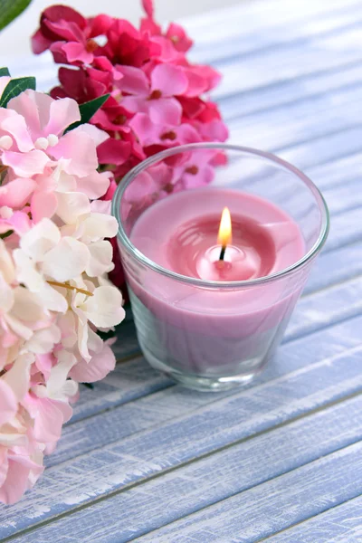 Schöne bunte Kerzen und Blumen, auf farbigem Holzhintergrund — Stockfoto