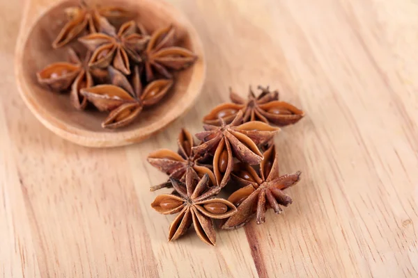 Star anise in wooden spoon, on wooden background — Stock Photo, Image