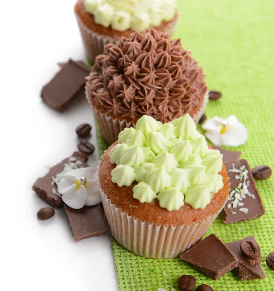 Cupcakes saborosos com creme de manteiga, em guardanapo de cor, isolado em branco — Fotografia de Stock