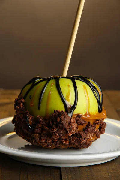 Candied apple on stick on wooden table — Stock Photo, Image