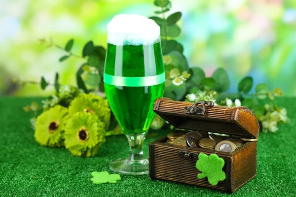 Glas van groene bier en werper met munten op gras close-up — Stockfoto