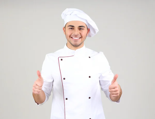 Professional chef in white uniform and hat, on gray background — Stock Photo, Image