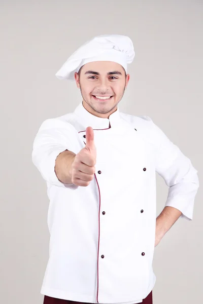 Chef professionnel en uniforme blanc et chapeau, sur fond gris — Photo