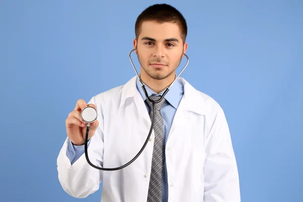 Mannelijke arts permanent op blauwe achtergrond — Stockfoto