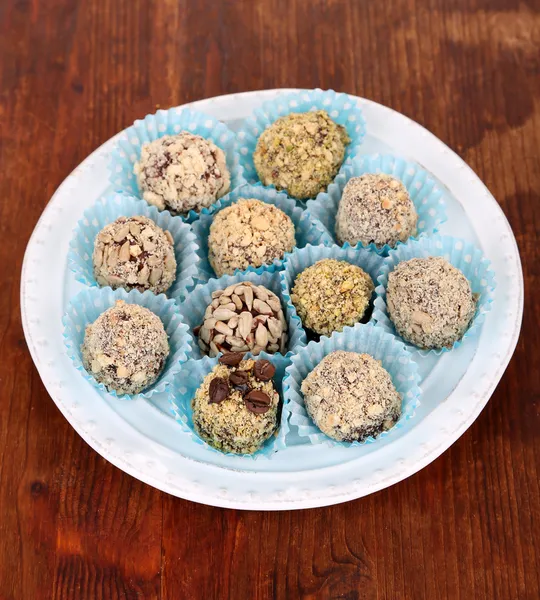 Set Schokoladenbonbons, auf Teller, auf Holzgrund — Stockfoto