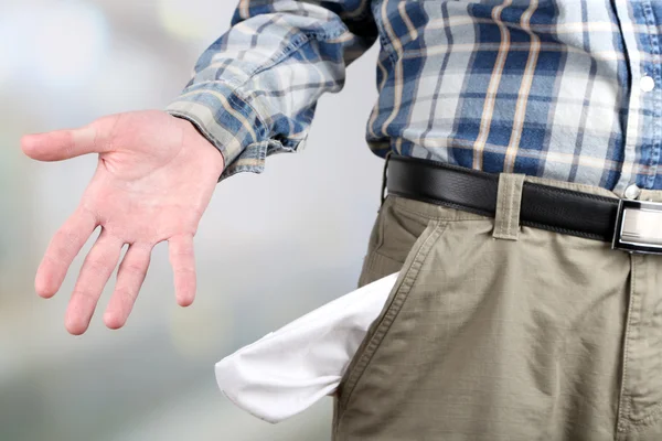 Homem mostrando seu bolso vazio no fundo brilhante — Fotografia de Stock