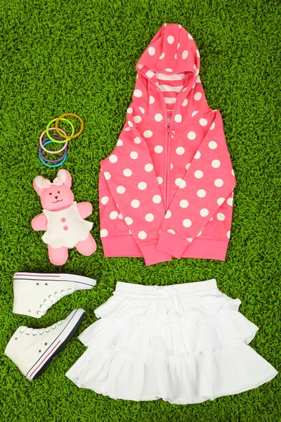 Beautiful clothes for little girl on green carpet — Stock Photo, Image