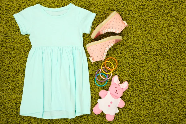 Beautiful dress and gumshoes for little girl on green carpet — Stock Photo, Image