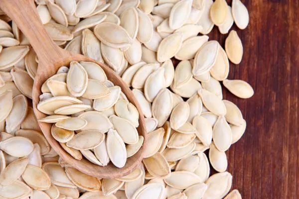 Pumpkin seeds in spoon on wooden background — Stock Photo, Image