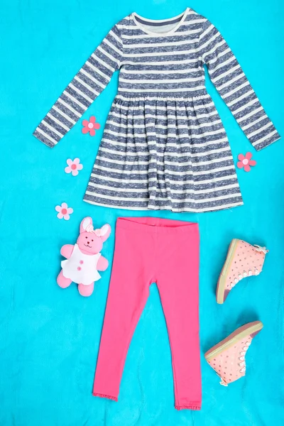 Красивая одежда для маленькой девочки на синем фоне — стоковое фото
